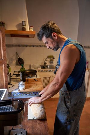 Focused man cutting bread in kitchen
