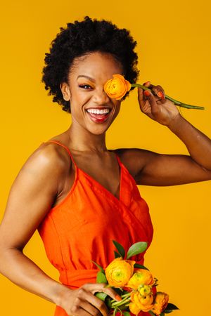 Smiling Black woman playing with ranunculus flowers