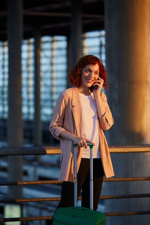 Smiling young woman talking on phone at station