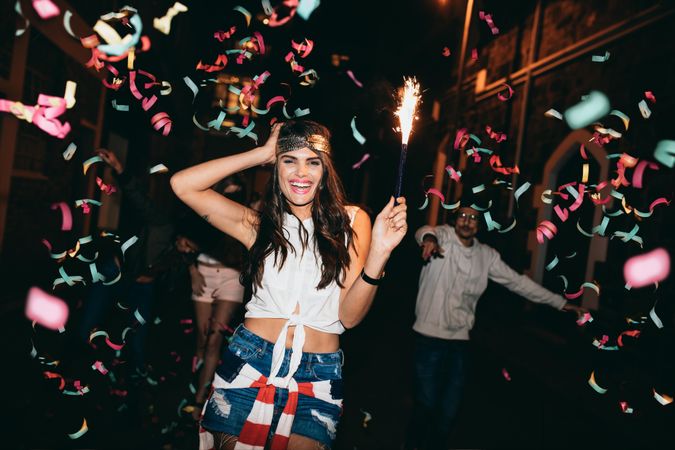 Happy young woman partying with her friends outdoors at night