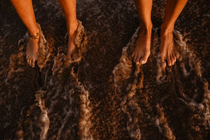 Crop legs near waving sea water