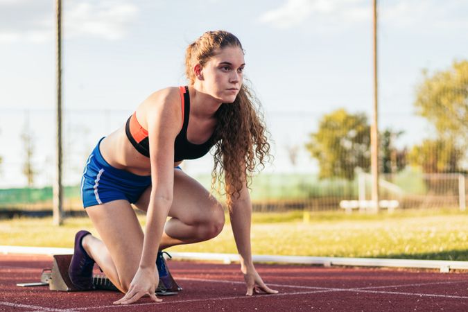 A female athlete getting ready to run on an athletics track.
