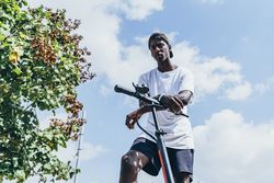 Black man riding on electric scooter in park