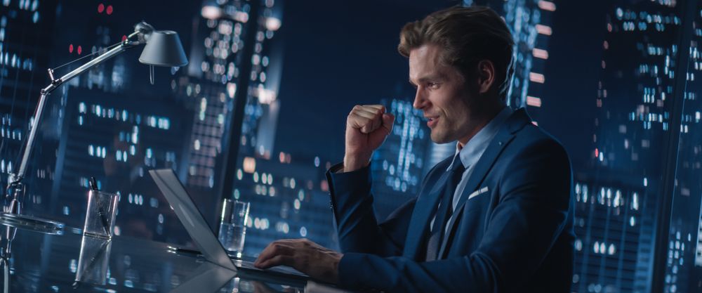 Successful Businessman Working on Laptop Computer in Big City Office Late in the Evening.