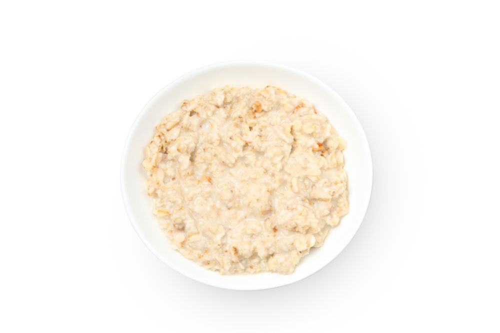 Plate with cooked oatmeal isolated on plain background