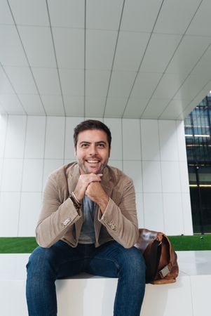 Cheerful manager sitting outside modern building