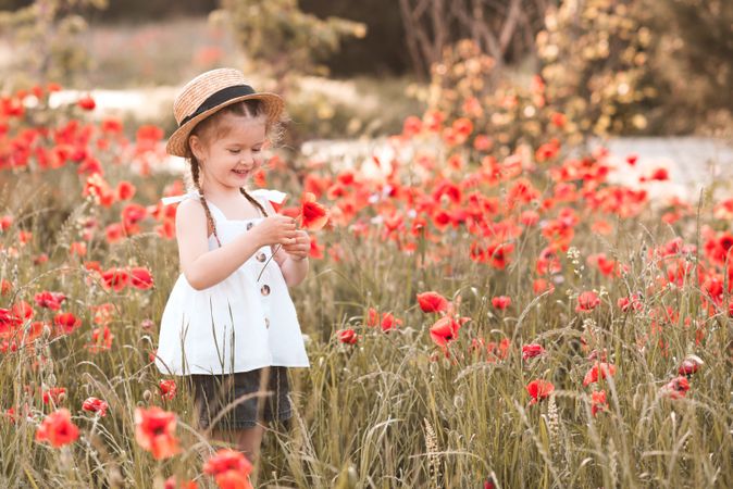 Girl in light dress standing in red flower field