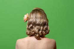 Back view of a blonde woman with retro-style hair in green studio