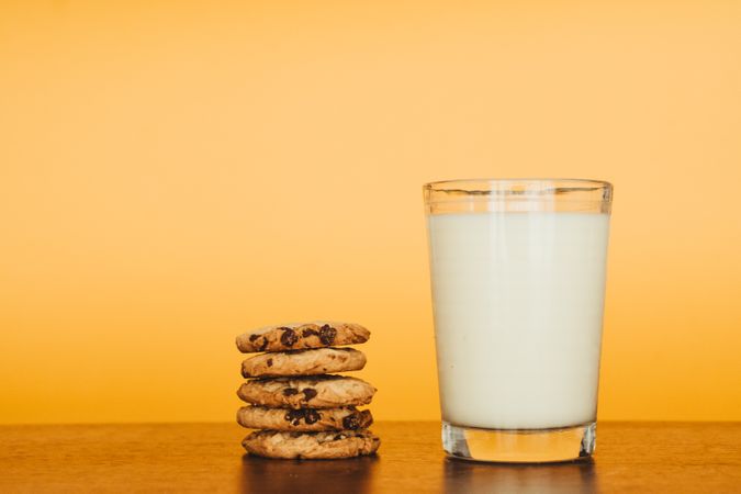 Delicious Breakfast: Cookies and Milk on a Wooden Table with an Orange Background.