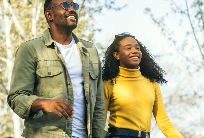 two stylish Black brother and sister smiling and walking in a park.