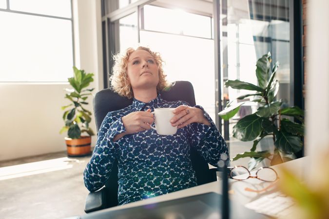 Woman enjoying coffee at home office desk