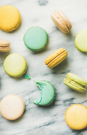 Scattered pastel macaron pastries, top view, vertical composition