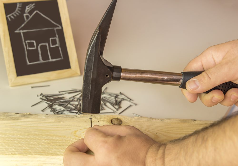 Mans hand hammering nail in wood