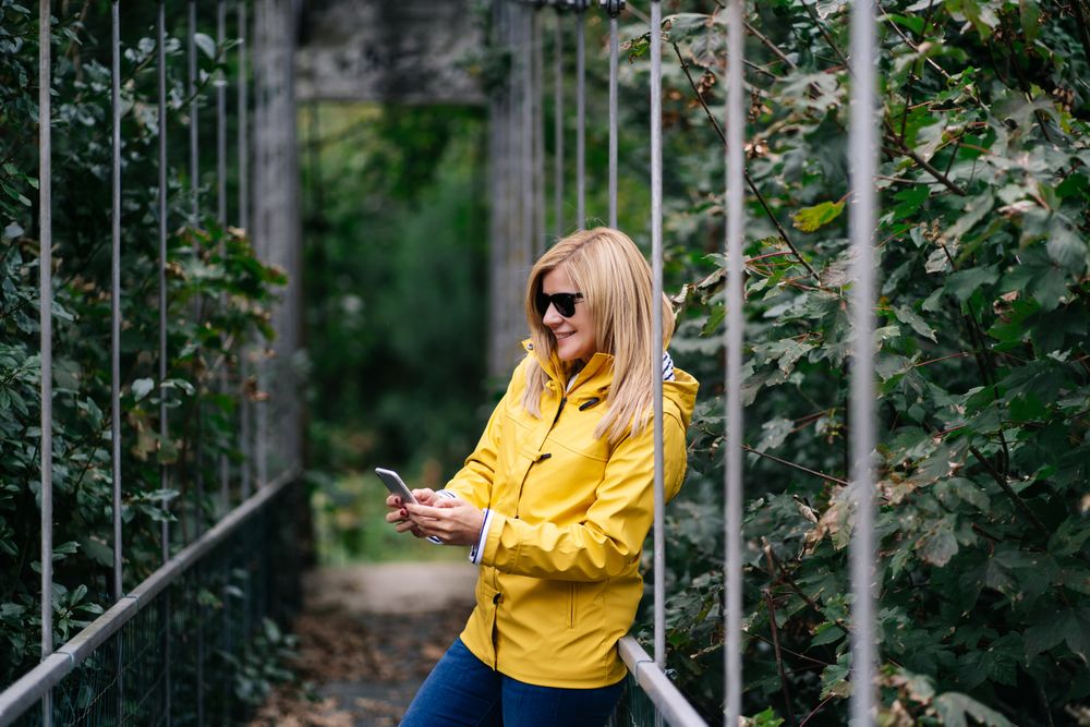 Happy female traveler taking selfie on suspension bridge in summer