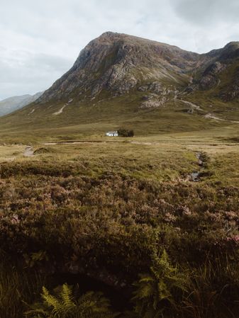 Lonely house in field by mountain