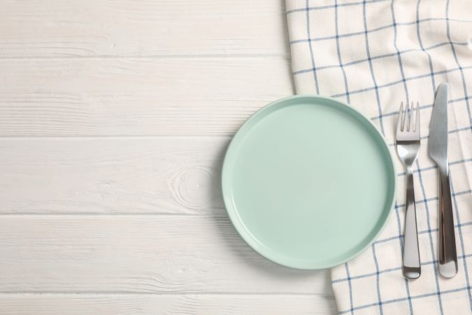 Kitchen towel with cutlery on wooden background, top view