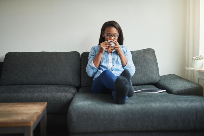 Woman lounging with tablet and cup of tea