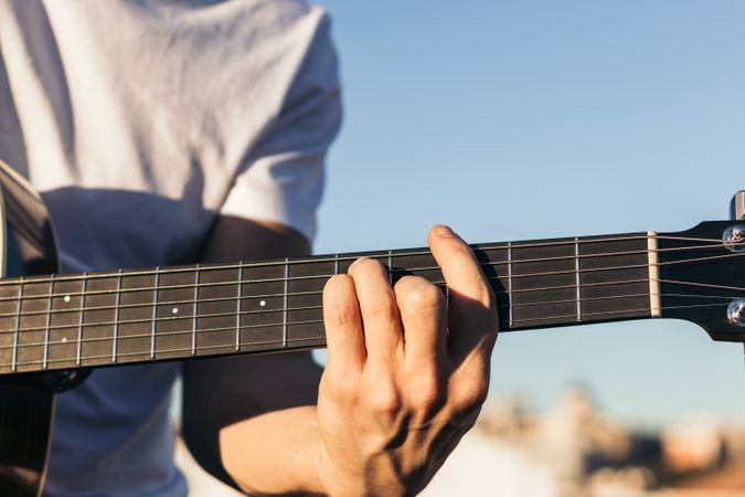 young man sitting playing acoustic guitar close-up