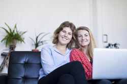 Happy couple using computer while sitting on couch