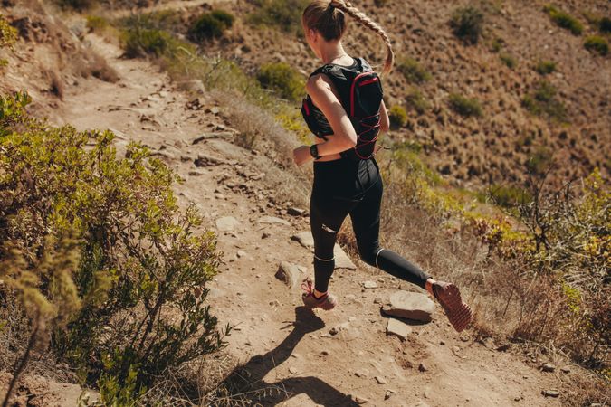 Woman running on rocky trails on the hillside