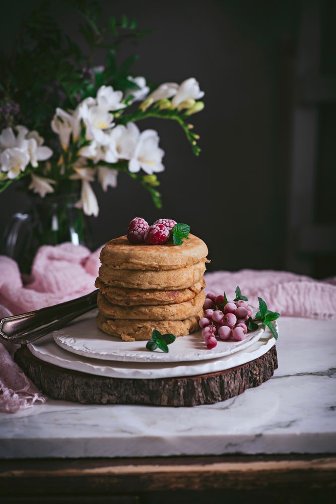 Pile of raspberry pancakes with honey on plate