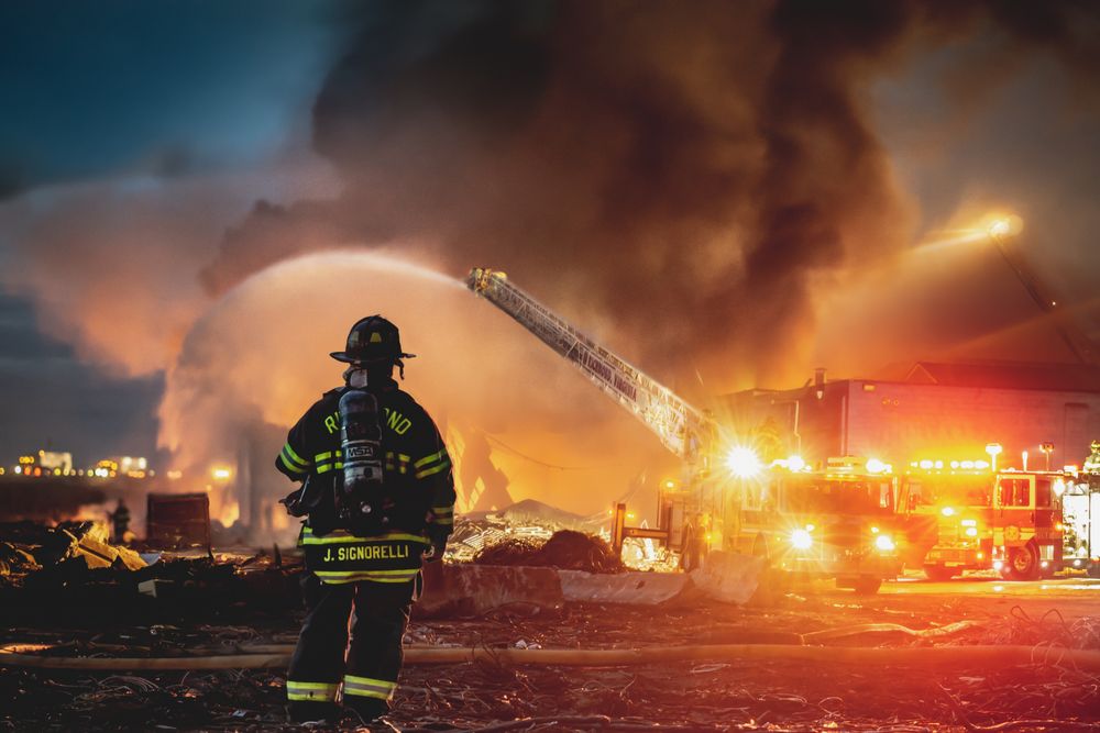 Firefighter extinguishing fire in a field during nighttime