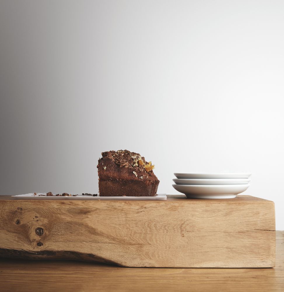 Side view of chocolate cake and plates on wooden board