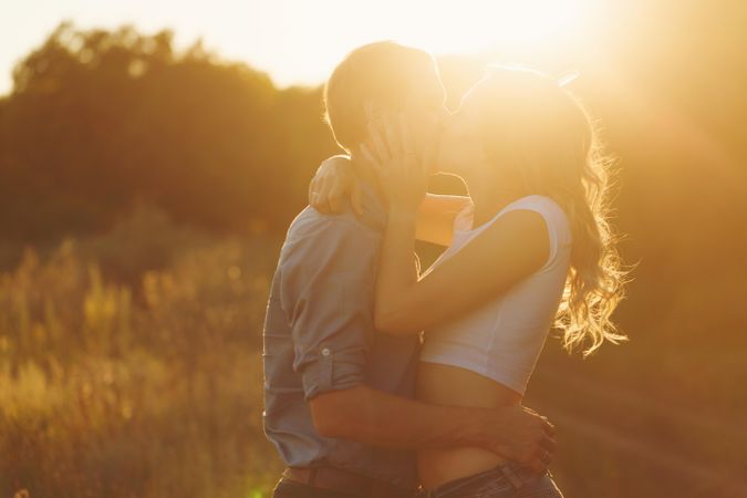 Backlit shot of couple being affectionate at sunset outside in summertime