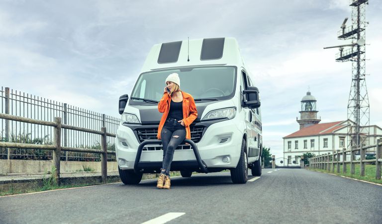 Female leaning in front of parked van while talking on phone
