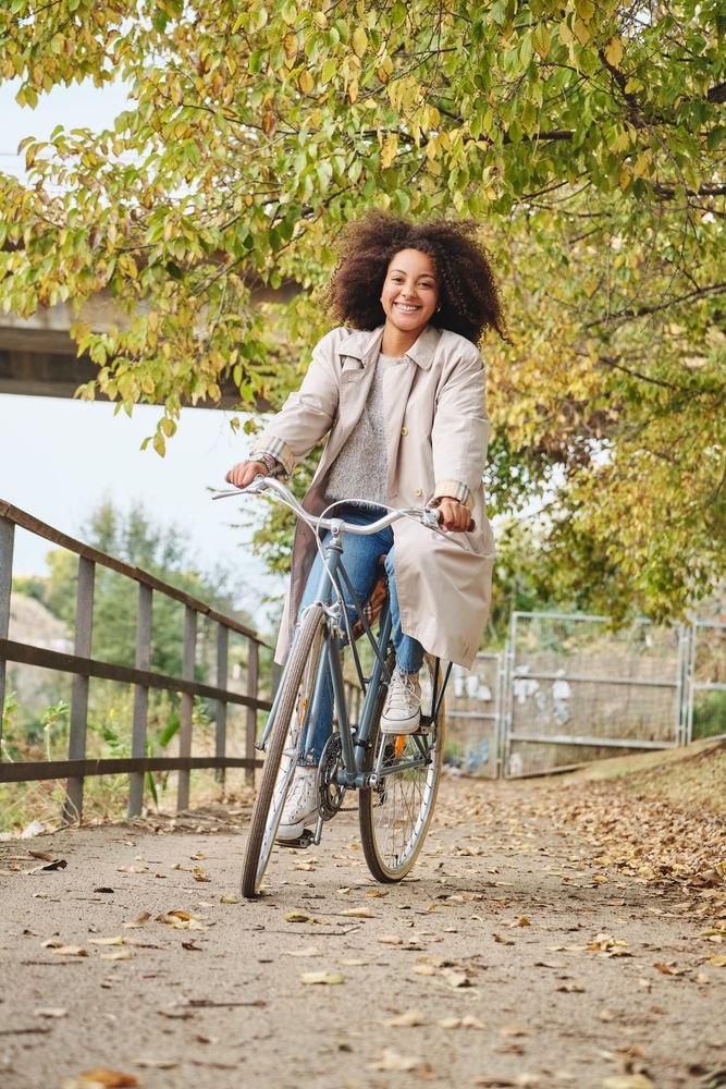 Happy Black female enjoying bike ride in park