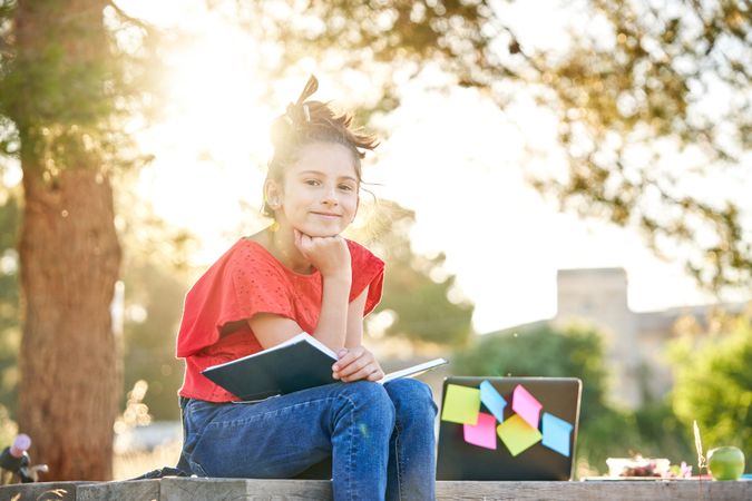 Cheerful kid doing homework in park
