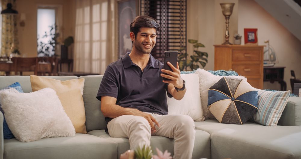 Indian Man Using Video Call On Smartphone At Home: Doing Remote Work, Conducting Video Meetings with Clients.