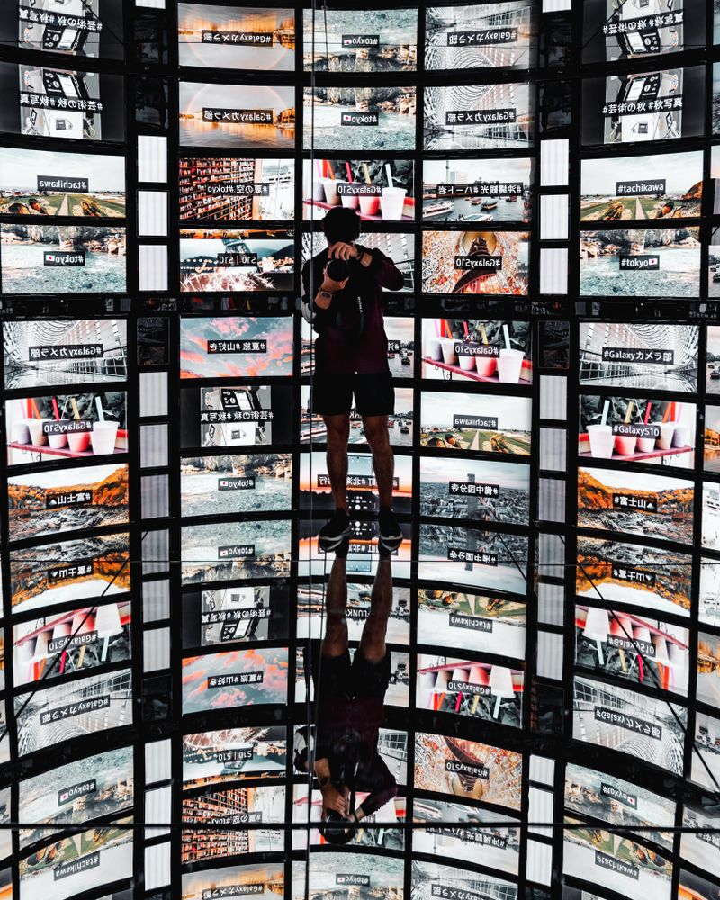 Photographer holding a camera and standing against screen display with mirror on floor