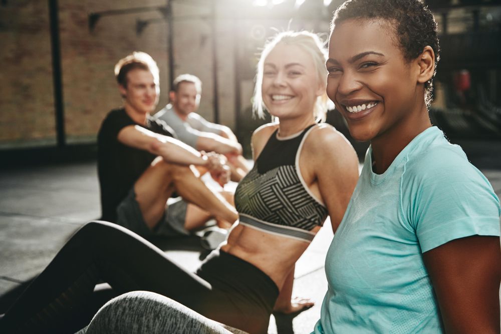 Multi-ethnic group of people smiling on gym floor after work out