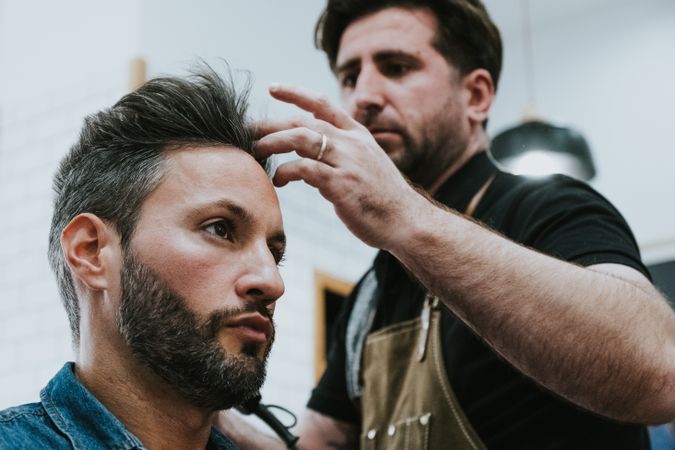 Barber combing hair to man in salon