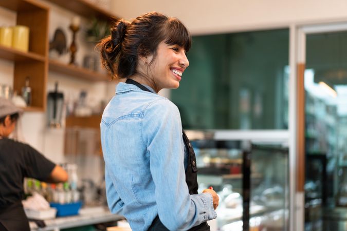 Happy coffee shop owner  in apron talking to customers