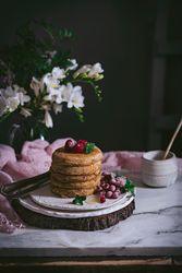 Pile of raspberry pancakes with honey on plate