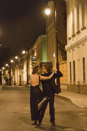 Man and woman dancing tango outdoor in the alley during night time