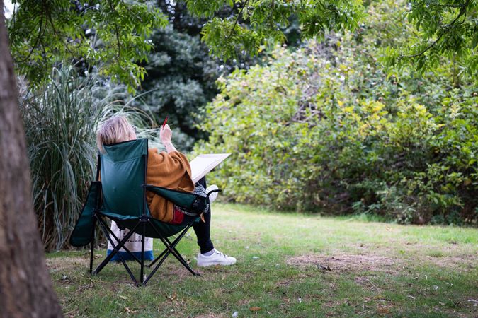 Woman in lush green park with drawing board