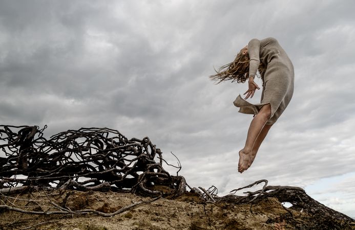Woman posing in air near dry twigs and blue sky