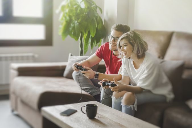 Couple with gamepads playing console