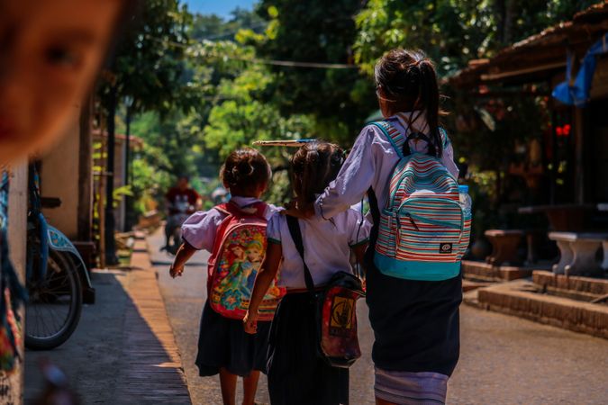 Back view of children in school uniform walking on the road