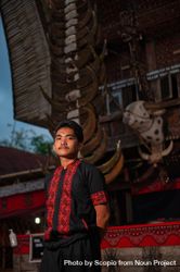 Young man from Tara Toraja community standing beside their traditional wooden house 4mBnQb