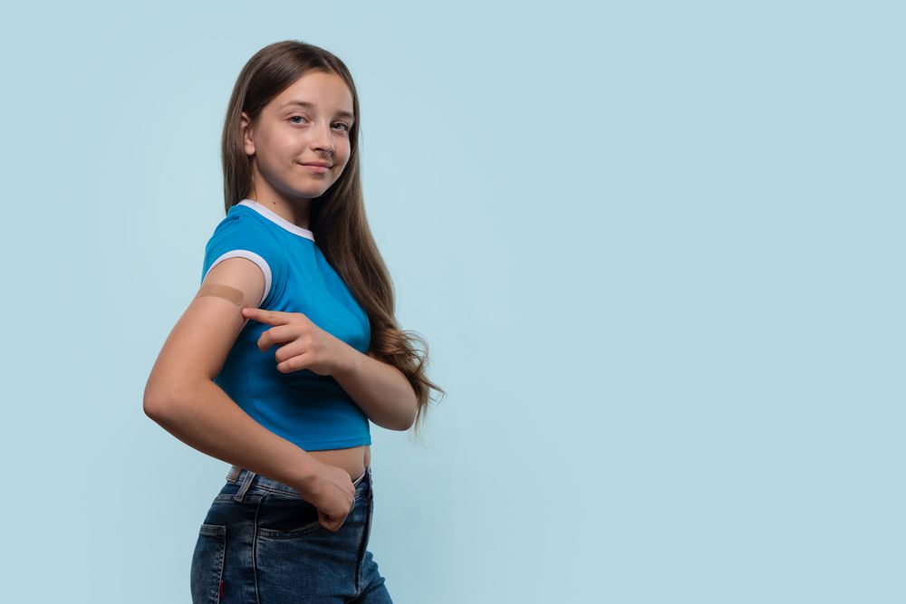 Young girl confidently pointing at bandage after vaccination