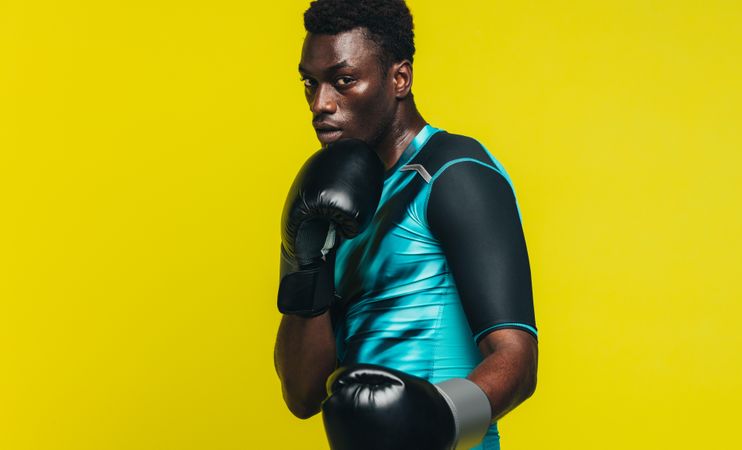 Black man in boxing stance over yellow background