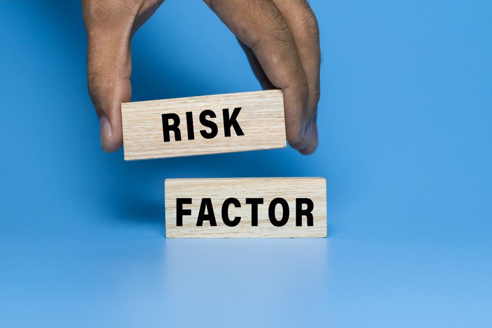 male hand put wooden blocks with risk factor words symbol concept isolated on blue background