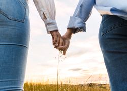 couple holding hands on a beautiful field at sunset