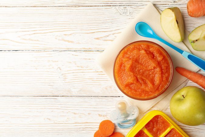Composition with baby food on plain wooden background
