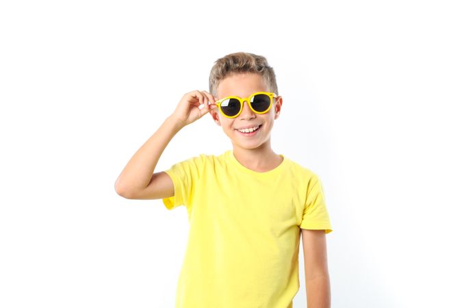 Boy in yellow t-shirt with sunglasses isolated on blank background
