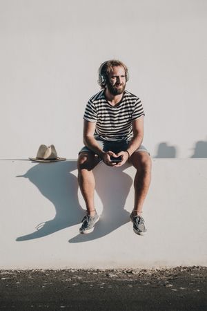Young male sitting with smartphone and headphones
